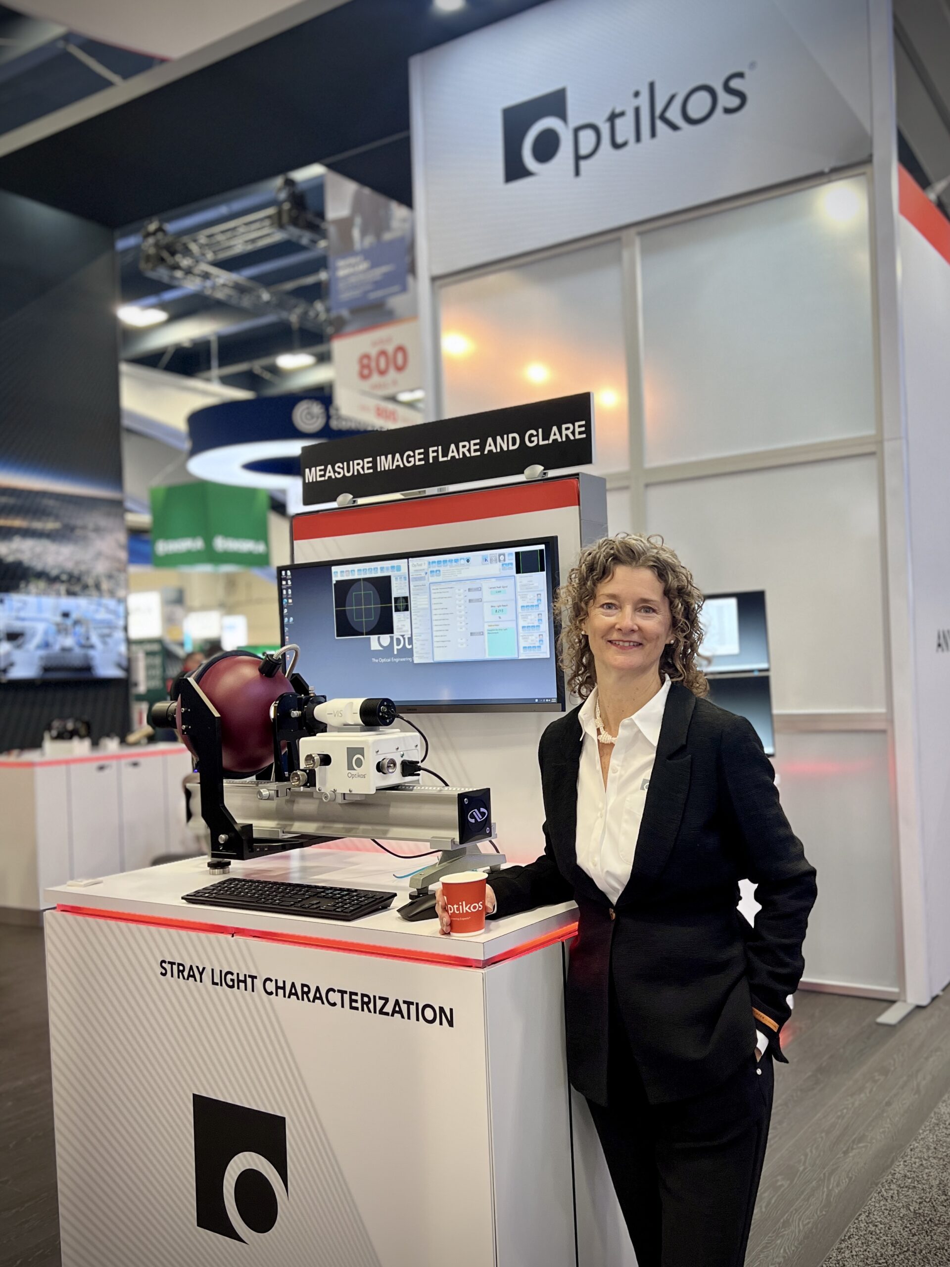 Woman in business suit standing in front of machinery in expo hall booth