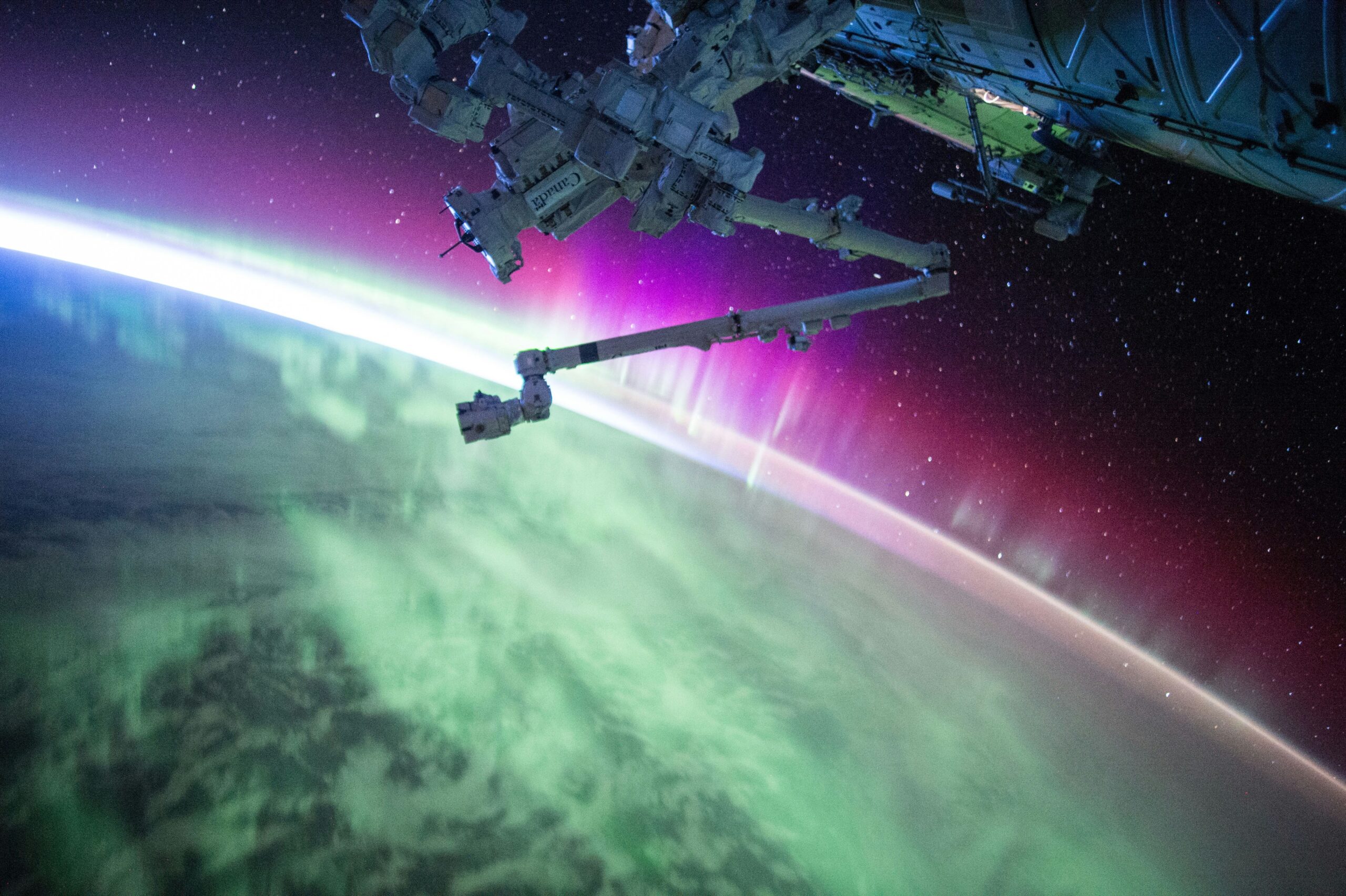 satellite hovering over earth with colorful aurora borealis lights in the atmosphere
